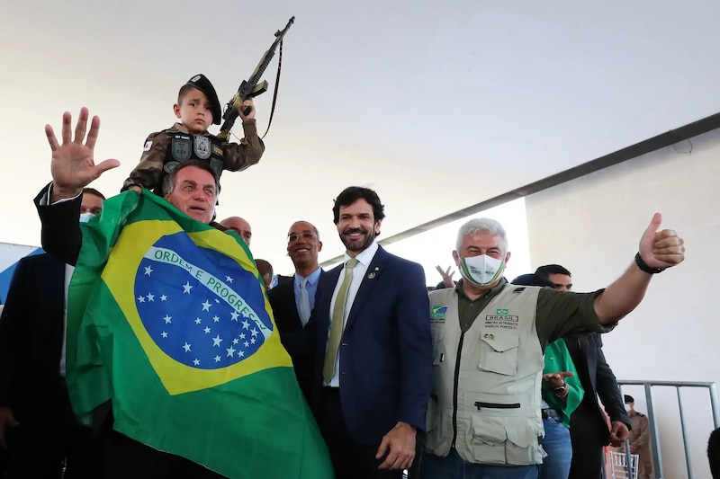 Jair Bolsonaro, el presidente de Brasil, sostiene en sus hombros a un niño que empuña un fusil