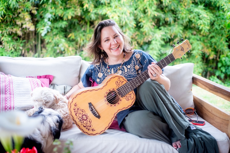 Mujer tocando la guitarra en un sofá