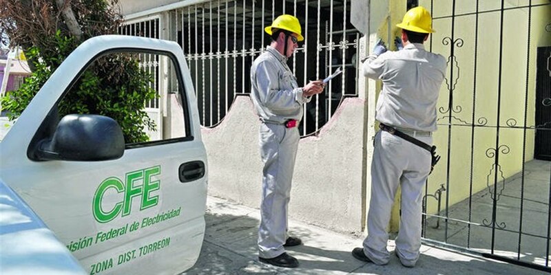 Dos trabajadores de la CFE realizan trabajos de mantenimiento en una línea eléctrica.