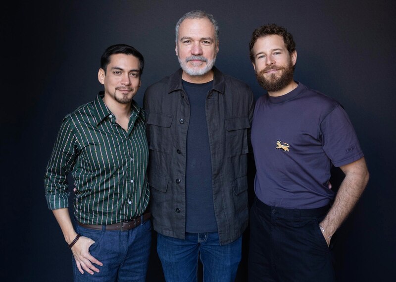 Tres hombres sonríen a la cámara.