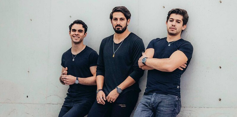 Tres hombres sonríen y posan para una foto.