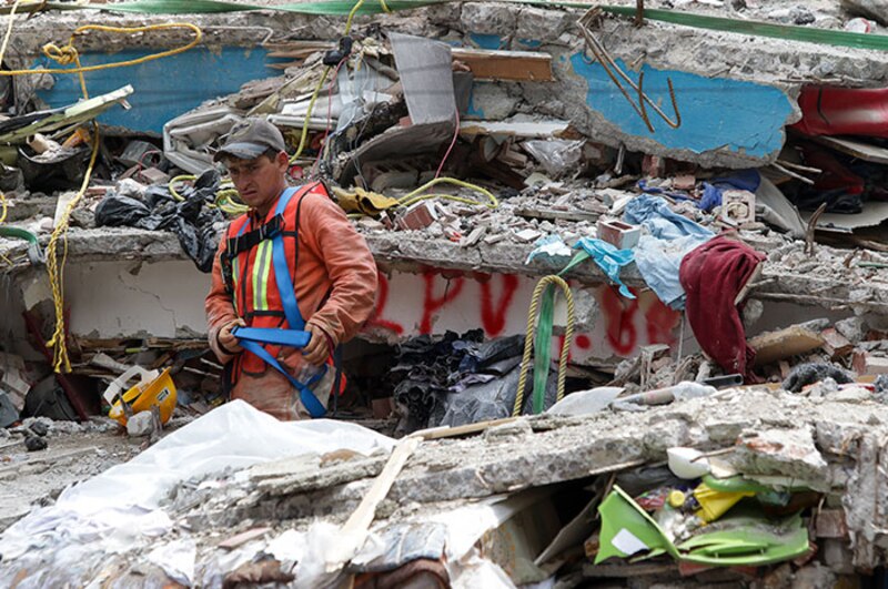 Un trabajador de rescate busca sobrevivientes entre los escombros de un edificio derrumbado por un terremoto.