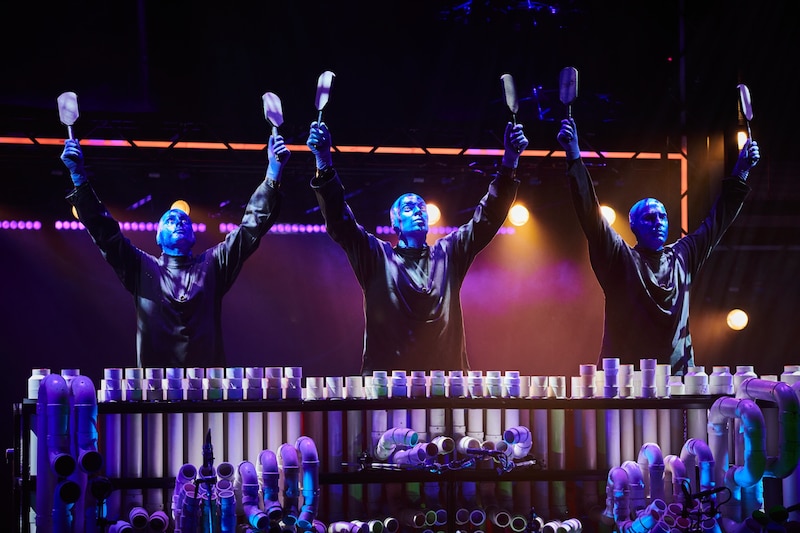 Blue Man Group tocando instrumentos musicales hechos de tubos de PVC.