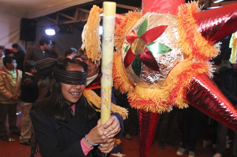 Una niña le pega a una piñata en una posada