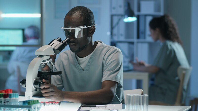 Científico negro usando un microscopio en un laboratorio