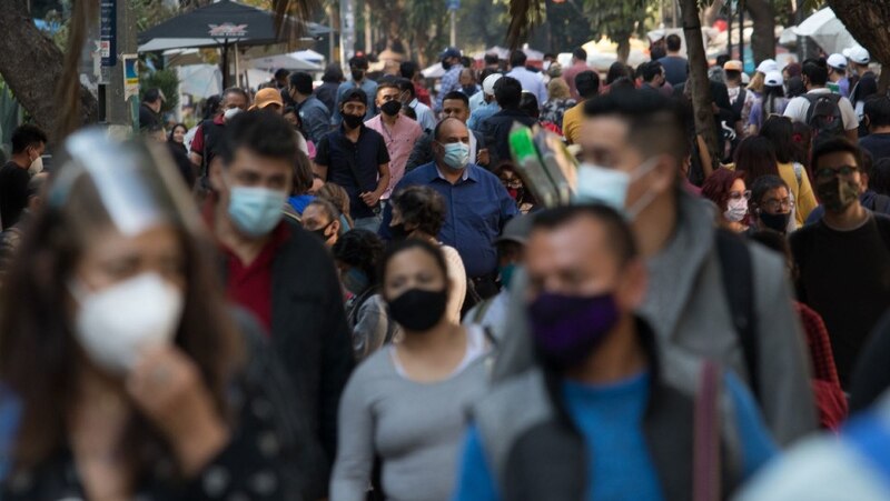 Multitud de personas con mascarillas caminando por una calle de la ciudad