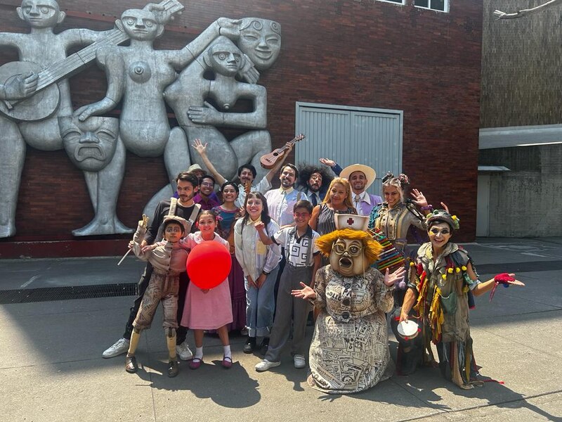 El elenco de la obra de teatro "La hija del mariachi" posa para una foto frente a un mural en la Ciudad de México.
