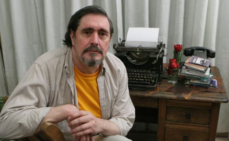 Escritor sentado en su escritorio con una máquina de escribir y rosas rojas