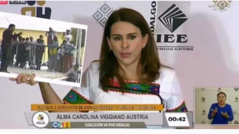 Title: La candidata Alma Carolina Viggiano Austria muestra una foto durante una conferencia de prensa.