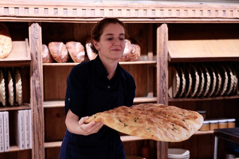 Una panadera sostiene una focaccia recién horneada