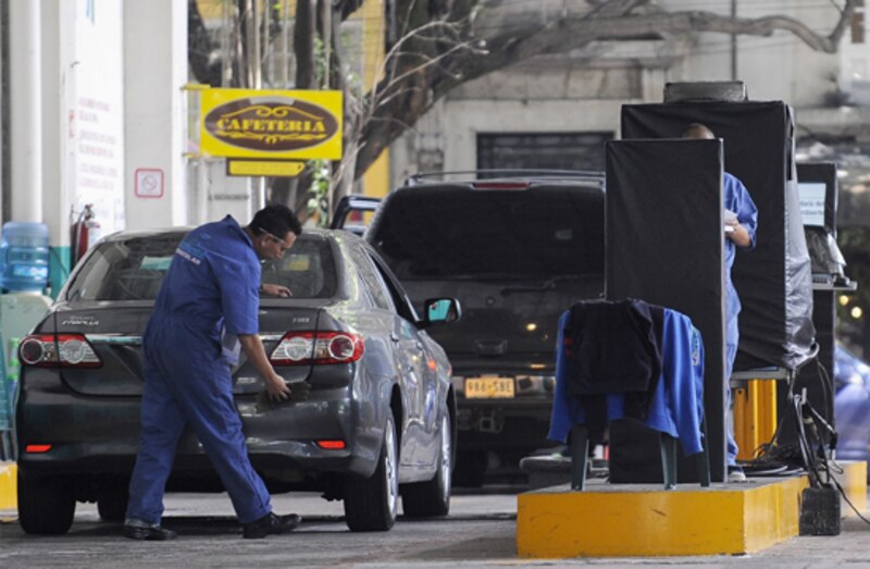 Un empleado de una gasolinera limpia el parabrisas de un coche.