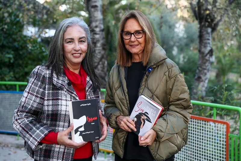 Dos mujeres sonríen mientras sostienen libros.