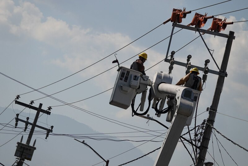 Dos trabajadores de la compañía eléctrica arreglando un cable de alta tensión