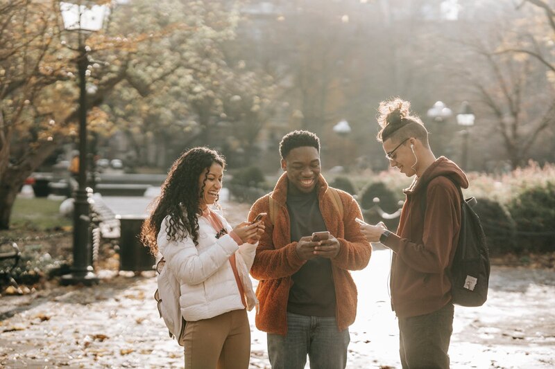 Jóvenes usando sus teléfonos móviles en el parque
