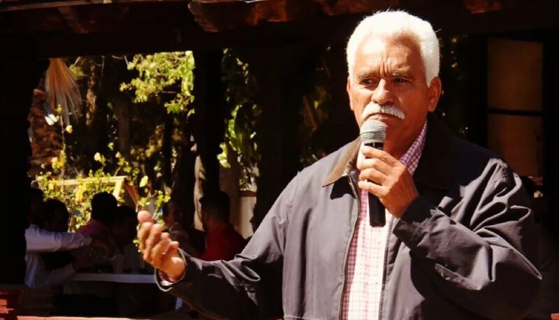 Un hombre mayor está dando un discurso ante un micrófono.