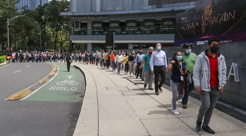 Larga fila de personas esperando para entrar a un restaurante