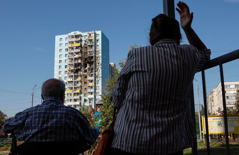 Anciano y mujer miran un edificio dañado