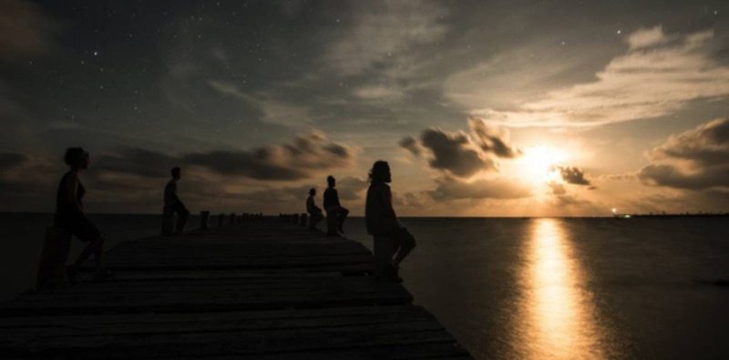 Un grupo de personas viendo la puesta de sol en un muelle.