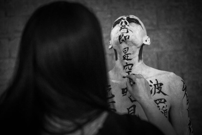 Un hombre con caracteres chinos pintados en el cuerpo