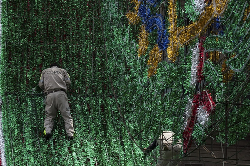 Un trabajador coloca adornos navideños en un edificio en la Ciudad de México