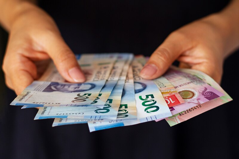 Mujer sosteniendo billetes de pesos mexicanos
