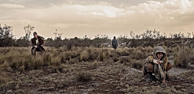 Un grupo de personas camina por un campo en busca de algo.