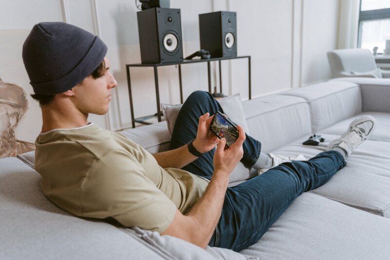 Un joven juega con su teléfono en el sofá