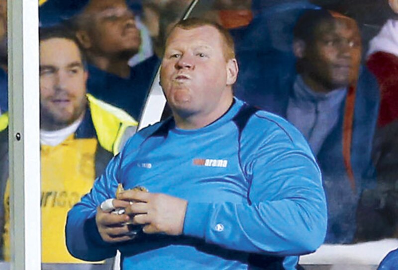 El entrenador del equipo de fútbol, comiendo un bocadillo en el banquillo
