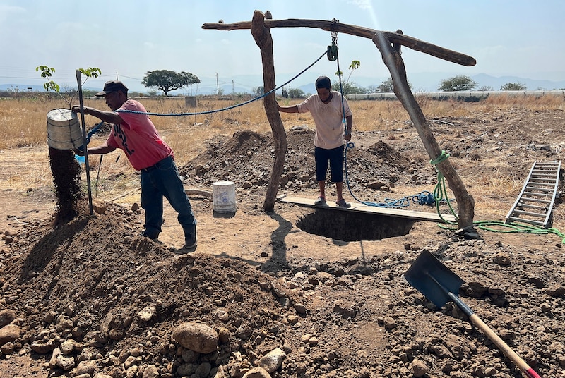 Dos hombres cavando un pozo en el campo