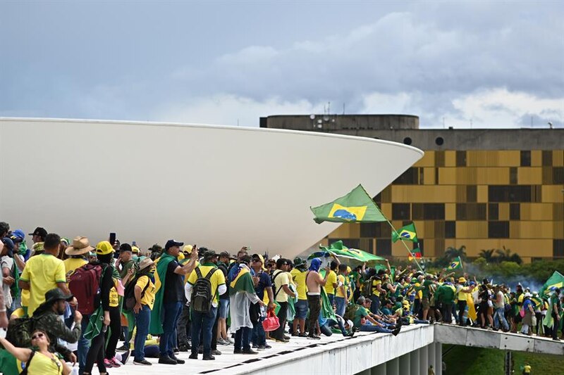 Multitud de personas ondeando banderas brasileñas en el exterior de un edificio gubernamental