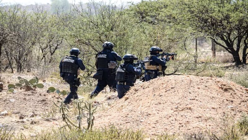 Policías estatales persiguen a un sospechoso en una zona rural