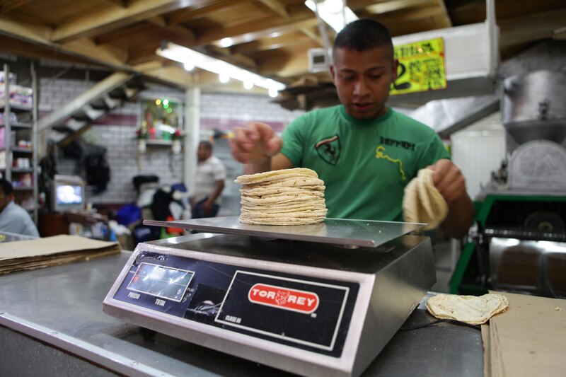 Un hombre pesa tortillas en una balanza