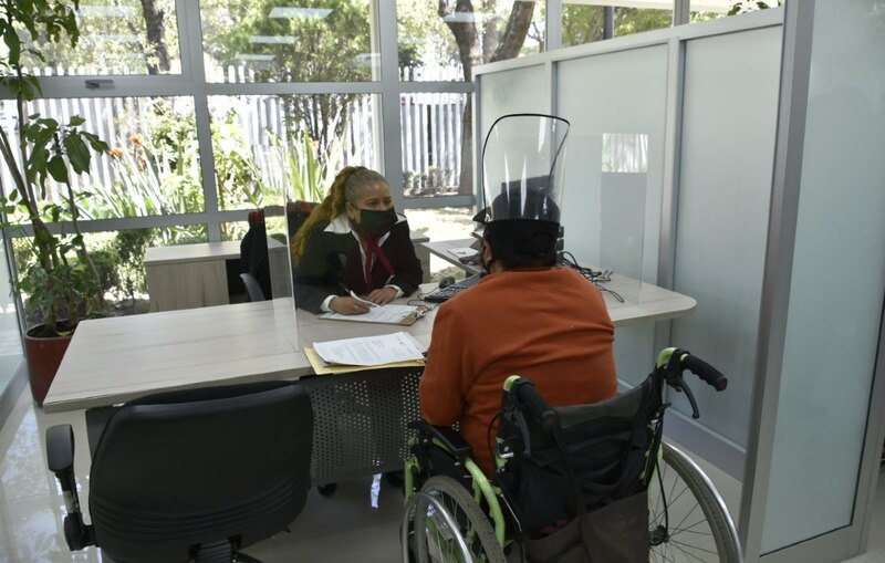 Mujer en silla de ruedas realizando un trámite en una oficina.
