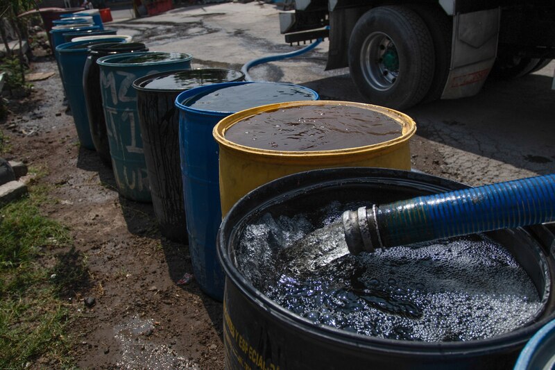 Camión cisterna llenando barriles de agua