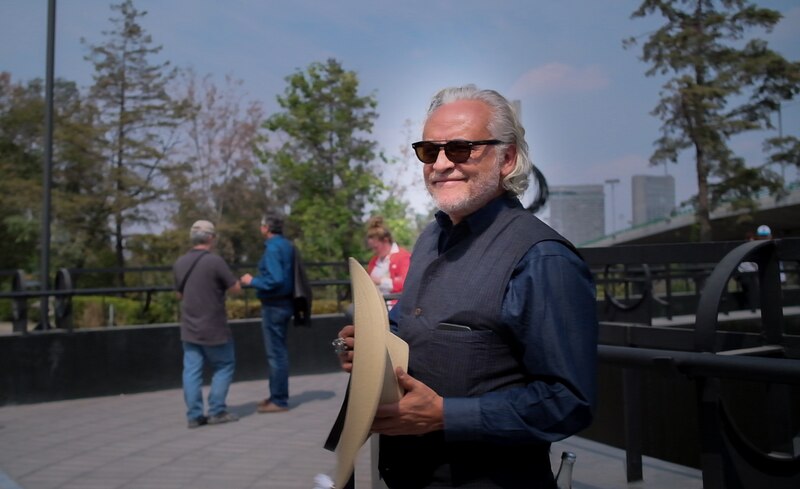 Un hombre con sombrero y gafas de sol sonríe a la cámara.