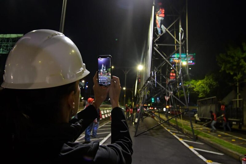 Un trabajador de la construcción toma una foto de un cartel en la noche