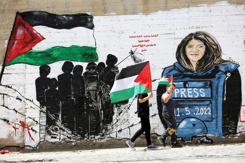 Niña palestina camina junto a un mural de la periodista asesinada Shireen Abu Akleh