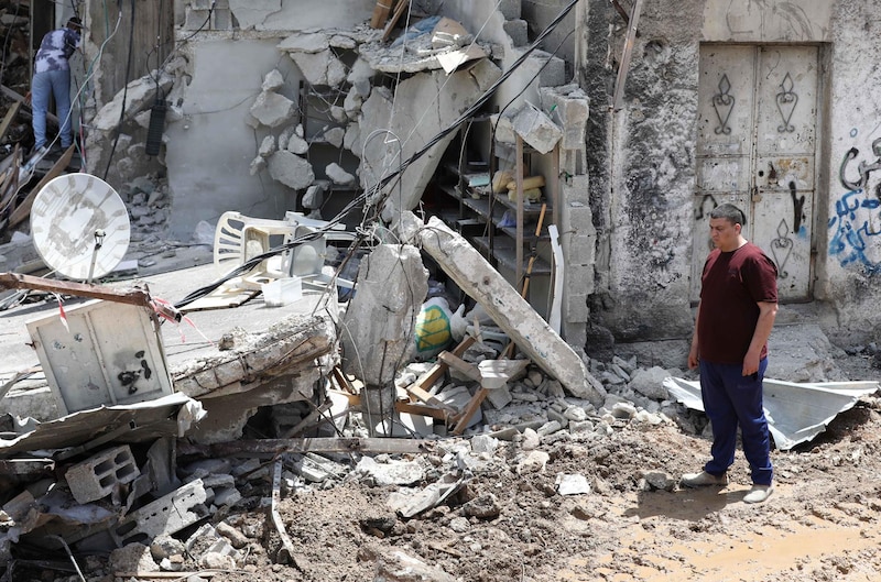 Un hombre inspecciona los daños en su casa después de un ataque aéreo en Gaza