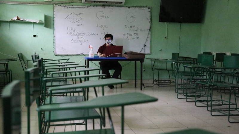 Profesor da clases online en un aula vacía