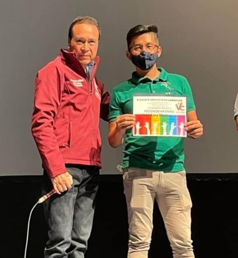 Entrega de reconocimiento a un estudiante por su participación en un concurso de oratoria.