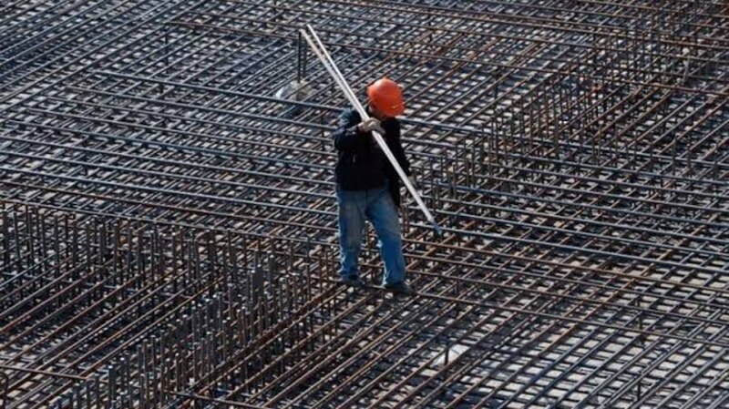 Trabajador de la construcción colocando barras de refuerzo en una losa de cimentación.