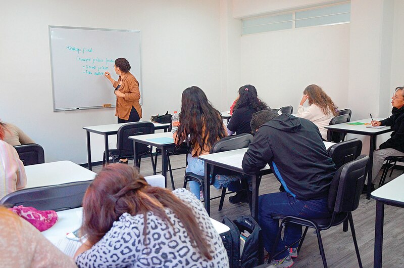 Profesora dando clase en un aula.