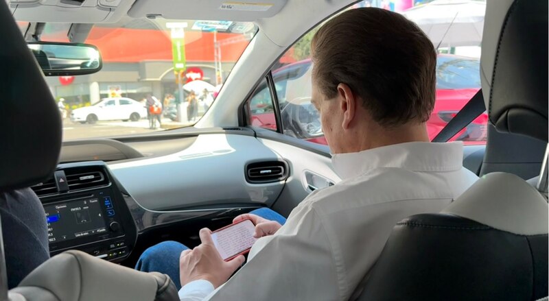 Un hombre mirando su teléfono mientras conduce