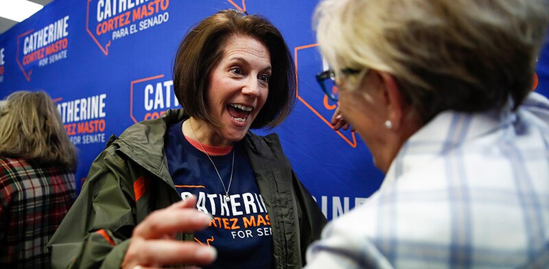 La senadora Catherine Cortez Masto se ríe con una mujer en un evento de campaña.