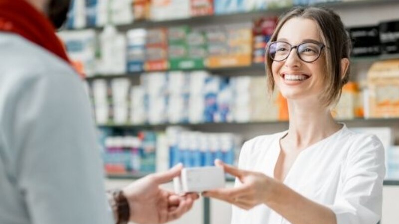 Farmacéutica entrega medicamento a un cliente