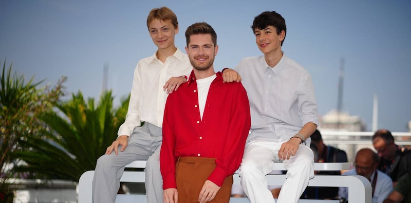 Tres jóvenes actores posan en la alfombra roja de un festival de cine.