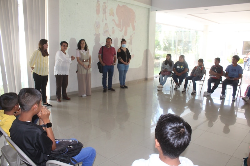 Estudiantes escuchando a una maestra en el aula