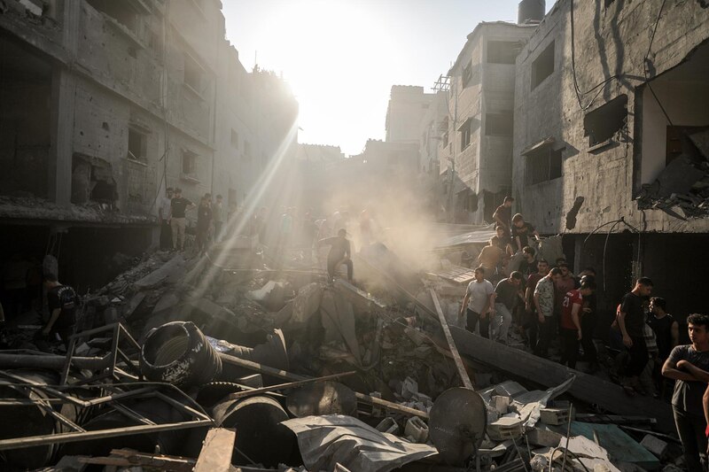 Civiles caminan entre los escombros de un edificio destruido en Gaza