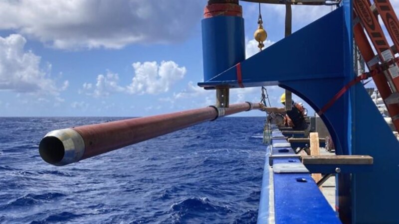 Un científico sostiene un tubo de metal sobre el océano