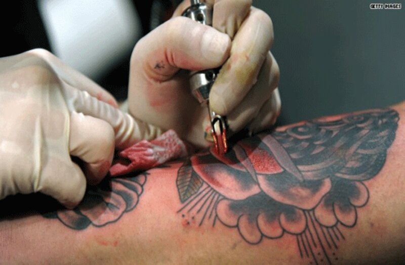 Mujer tatuándose una rosa en el brazo